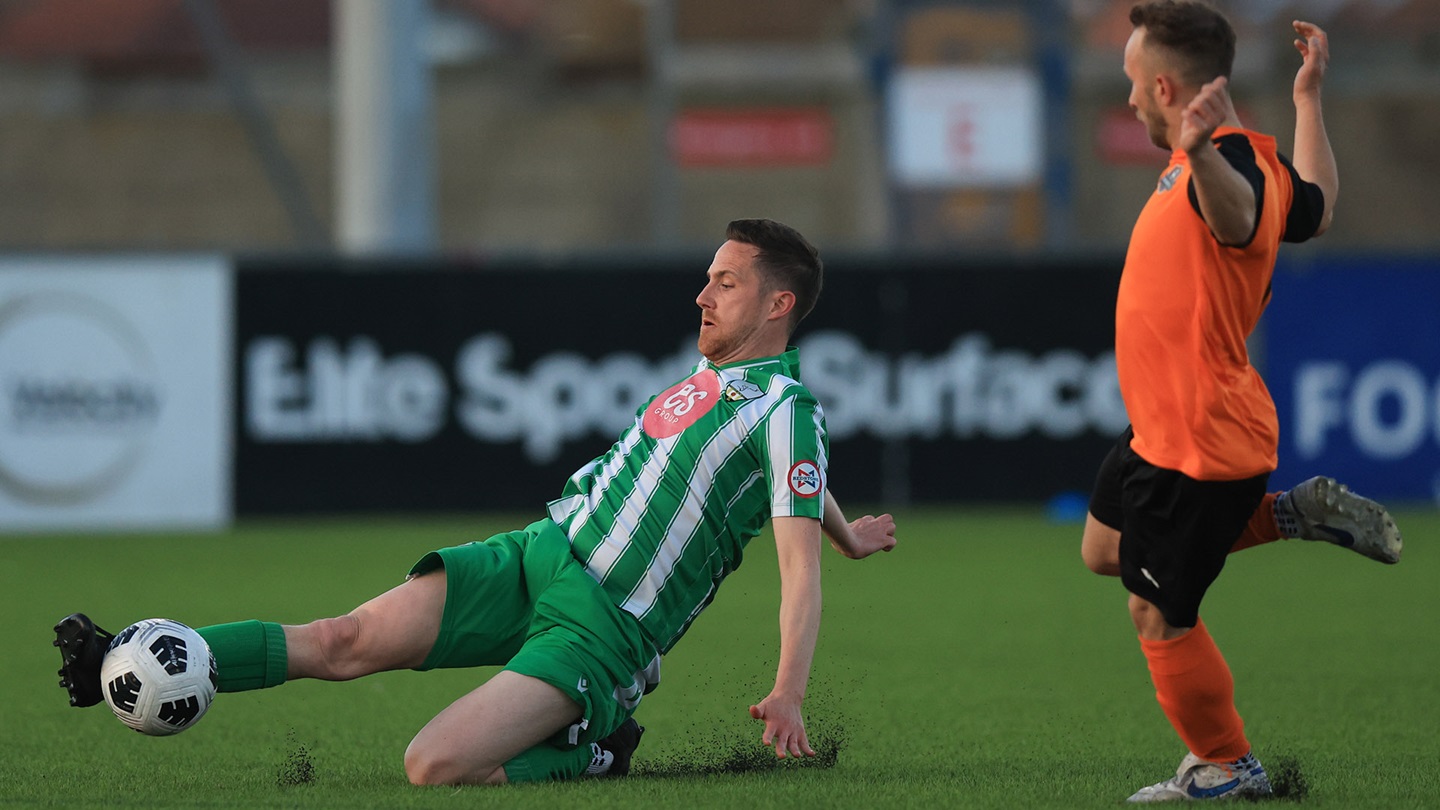 A Reserves player reaching for the ball in a sliding challenge